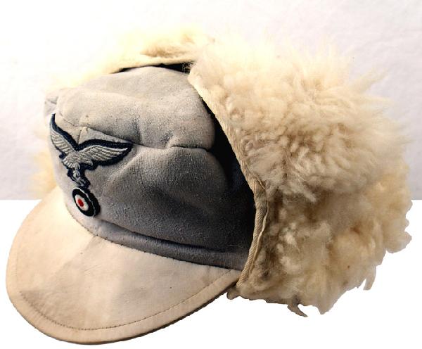 German WWII Luftwaffe white pelzmutze hat cap: E-160 Luftwaffe white leather visored "pelzmutze". Fleece lined interior and turn-up earflaps. Embroidered EM type. Luft eagle/swastika and rosette sewn to front. Cloth label, with maker "BEROLINA BER