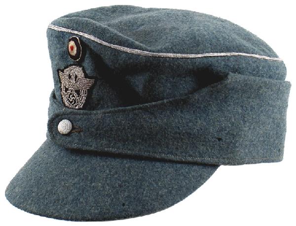 German WWII Police officer winter cap: E-158 Police officer’s “new style” winter cap. Similar to the M43. Green wool with pull-down sides and a silver wire cord piped crown. Machine sewn embroidered silver-gray eagle/swastika/wreath 