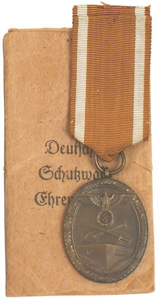 German WWII Westwall Medal: B-146 Westwall Medal. Large eagle/swastika/crossed shovel/sword above a bunker. Awarded to all personnel who helped construct Germany's West Wall fortifications. With issue envelope marked "…Wernste