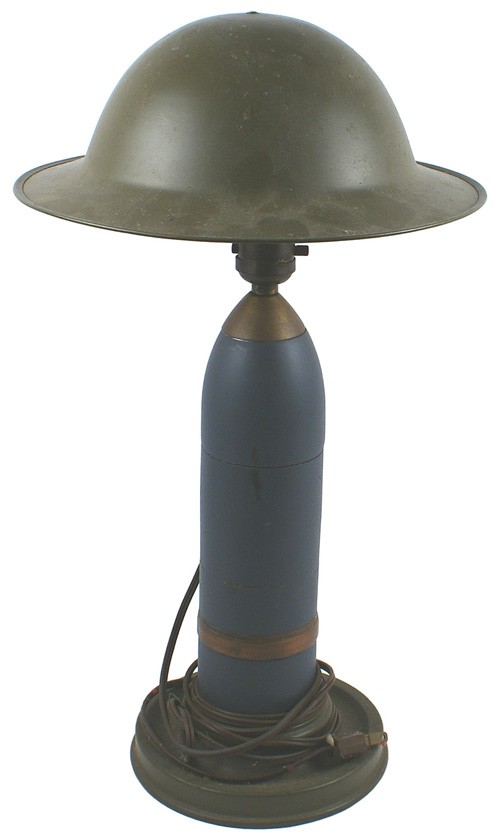 U.S. WWI trench art table lamp: H-165 Souvenir table lamp. French 75mm artillery projectile. 11 ½" tall shell, with a gas ring and fuse, mounted on a round metal base. Socket/light bulb holds a light weight parade type "doughboy" h