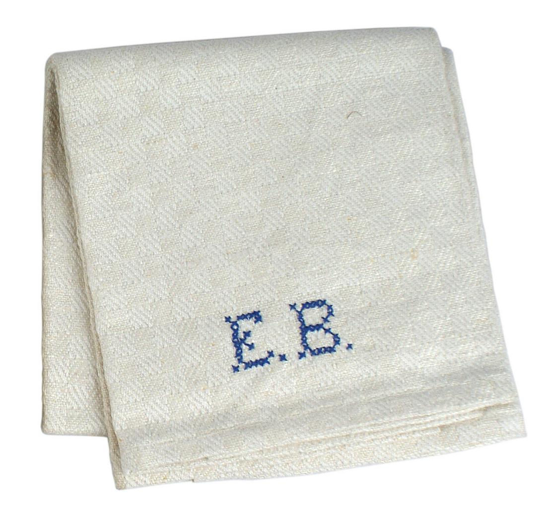 German WWII Eva Braun hand towel: A-011 Eva Braun hand towel. White cotton with a subdued pattern of continuous "diamonds". 7/8" high blue cross stitched initials "EB" near one border. Ribbon loops on the reverse on both ends. Overall