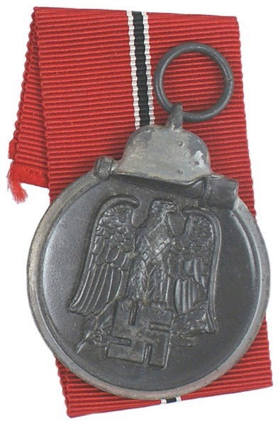 German WWII Eastern Front Medal: B-116 Eastern Front Medal. Darkened finish on silvered perimeter with a helmet/stick grenade. Obverse bears a relief black-gray eagle/swastika. Reverse: "WINTER BATTLE IN THE EAST 1941/42". II
