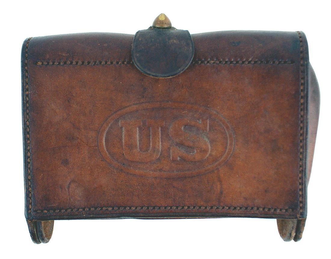 US M1876 McKeever cartridge box: K-133 US M1876 McKeever brown leather cartridge box. 3 1/2" x 6 1/2" with a top brass finial/locking strap. Embossed oval holding "US" on front. Two rows of 10 web cartridge holder loops for pistol am