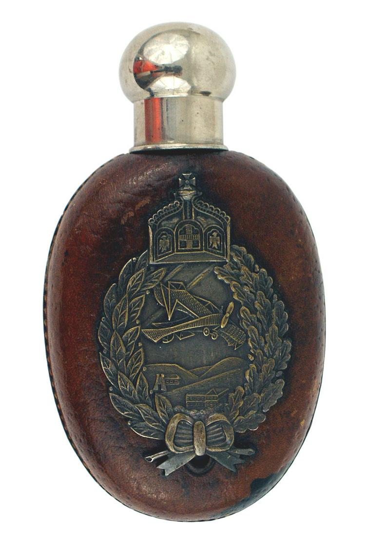 German WWI glass pocket flask: G-001 WWI period glass pocket flask. Age toned protective leather covering. "Slit" window on reverse. Silvered domed screw-on cap. Old flat type reproduction Prussian Pilot's Badge affixed to the fron