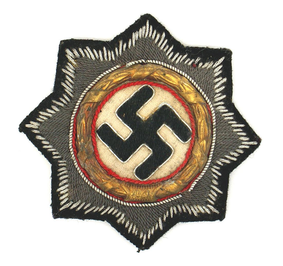 German WWII Waffen SS German Cross in Cloth: B-056 German WWII Army Waffen-SS/Army Panzer German Cross in Cloth. Relief embroidered black swastika on white field within an age toned gilt metal wreath. All on a gray starburst with a black perimet
