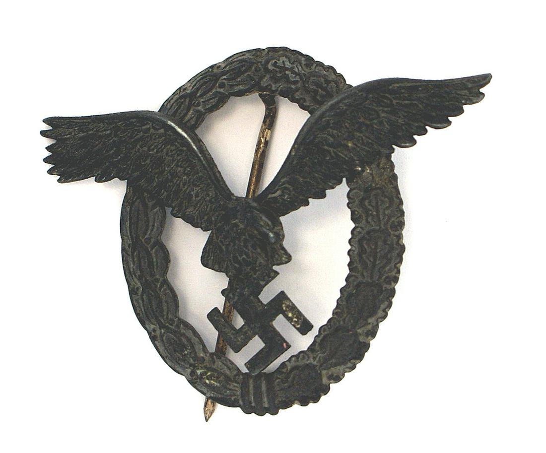 German WWII Luftwaffe Pilot Badge: B-057 Luftwaffe Pilot's Badge. Flying eagle clutching a swastika on an open oak/linden leaves wreath. Wartime in dark metal. Traces of the silver finish can be seen in the recesses of the eagle's feat