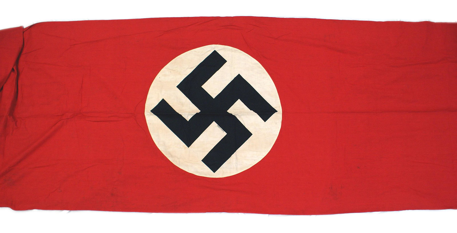 German WWII NSDAP building banner: H-041 Third-Reich N.S.D.A.P. building banner. Large black printed swastika on a 29" diameter white circle, sewn to a 32' x 84" red field. The name of the town of "Denkendorf 4" is printed on the edge 