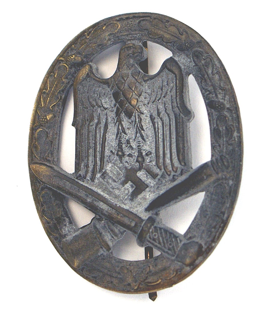 German WWII General Assault Badge Silver: B-062 General Assault Badge - Silver. Eagle/swastika with crossed bayonet/grenade - on an open oak leaf wreath. Solid type - with 50% of the finish oxidized. Reverse maker marked "FRANK & REIF. STUTTG