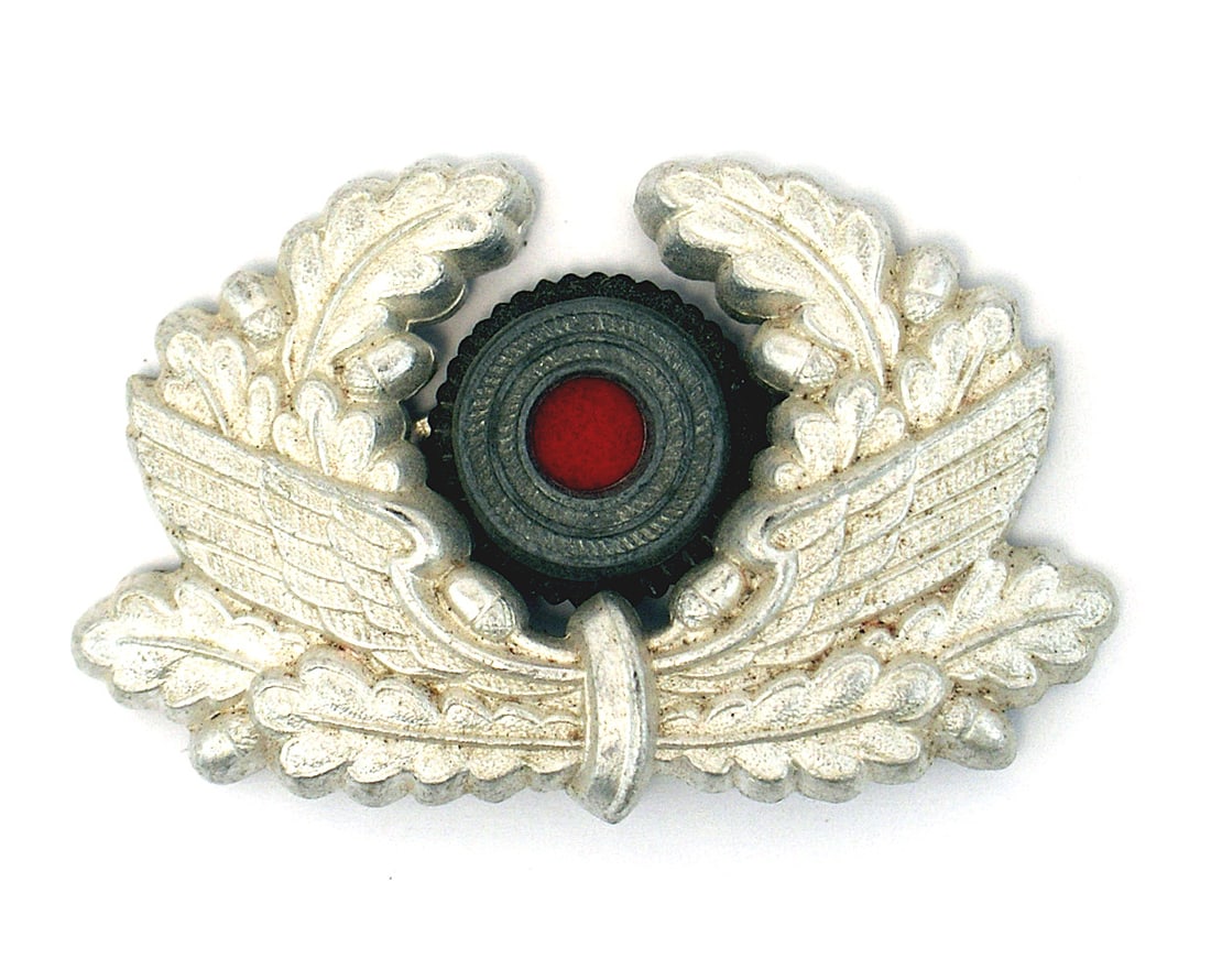 German WWII peaked cap insignia Bahnschutz: E-167 Lot of 2 Third-Reich peaked cap insignia: (1) Bahnschutz winged wheel/oak leaf wreath. Silvered highlights. With a rosette. (2) 5 7/8" long winged wheel with an attached blue center rosette. II