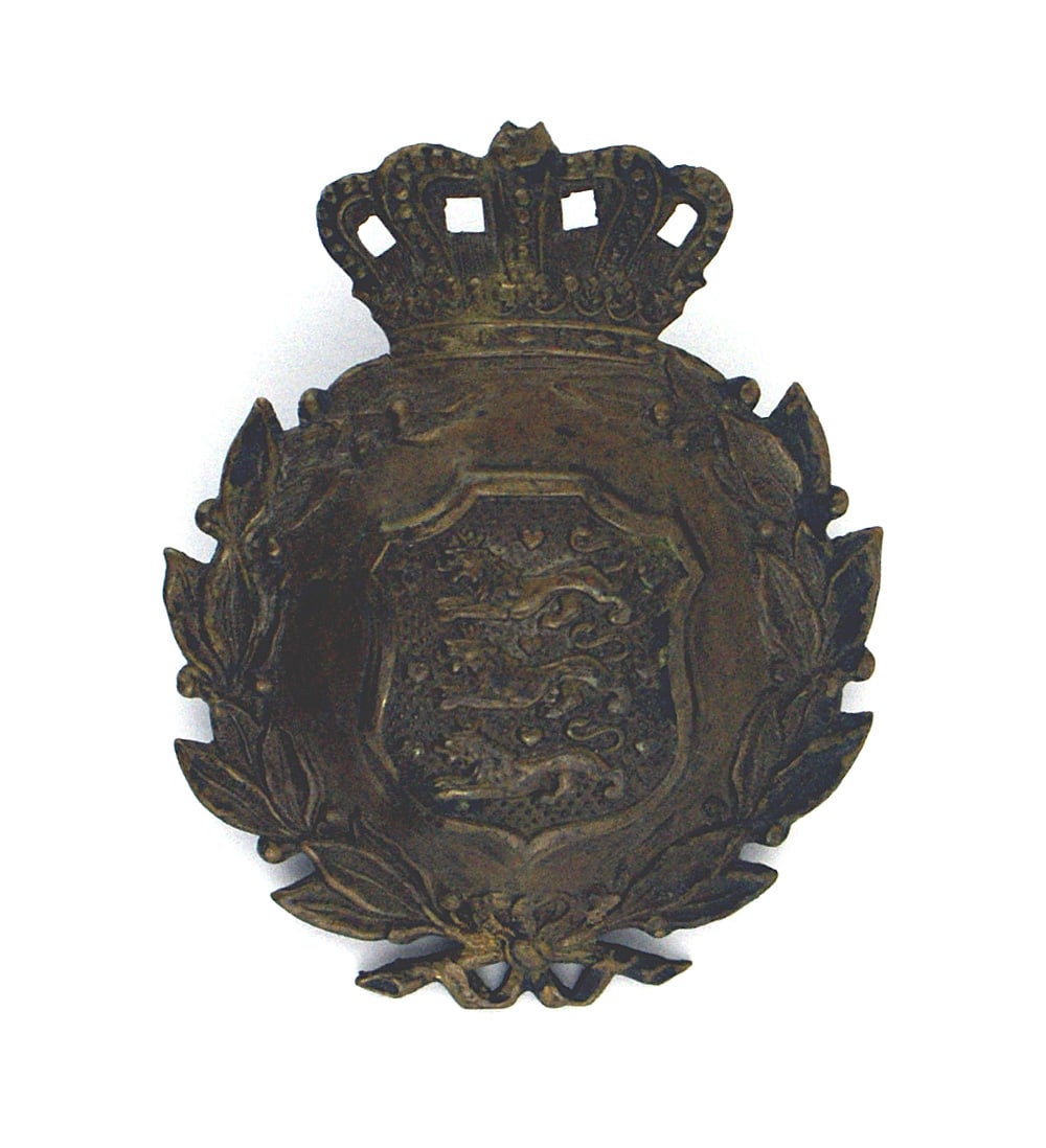 Badge for Danish M1923 helmet: E-218 Helmet badge for the Danish M1923 helmet. Bronzed crowned oak leaf wreath holding a relief shield with three lions. Reverse has one part of a post. Small cross missing from top of crown. II