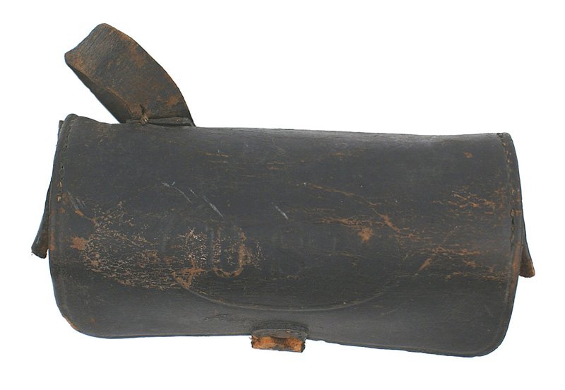 Post-Civil War Navy pistol cartridge box: K-46 Post-Civil War Navy leather pistol cartridge box. Trunk shaped with "USN" embossed on the flap which has a snap-button strap. Internal wood block which holds 6 cartridges and 2 cylinders. One bel