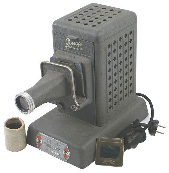 German WWII Hitler Youth slide projector: H-108 German WWII Hitler Youth slide projector. Made by Pouva. Large HJ metal label with "HJ Bildgerat". 9 1/8" x 8 3/4" x 5 5/8". Working condition. With one glass slide of a garden/resort and a comi