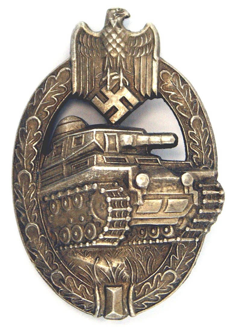 German WWII Tank Assault Badge Silver: B-041 German WWII Tank Assault Badge - Silver. Eagle/Swastika at top of an oak leaf wreath holding a panzer. Sculpted reverse with a maker's "AS" in a triangle logo. II