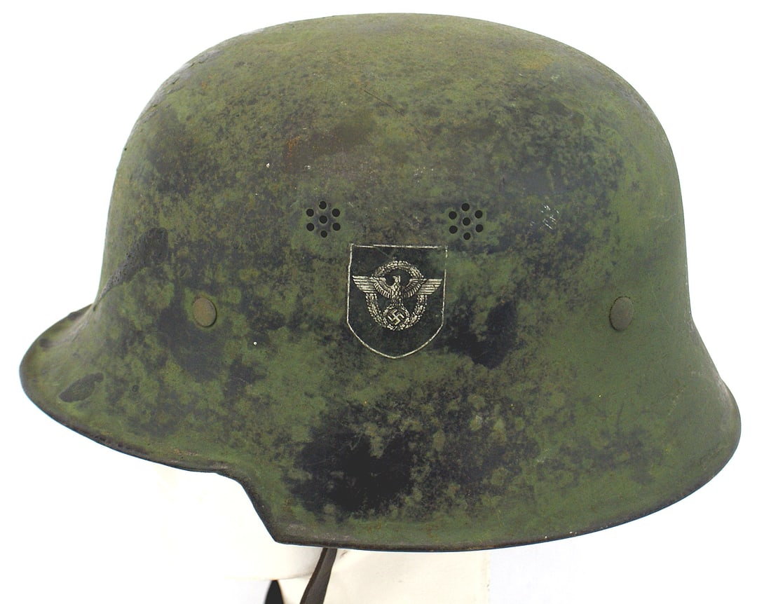 German WWII Fire Police helmet field use: E-025 German WWII Fire Police helmet converted to "field" use. An original double-decal black finish, painted over with a flat grass green. The Police eagle decal and the swastika shield (lightly cove