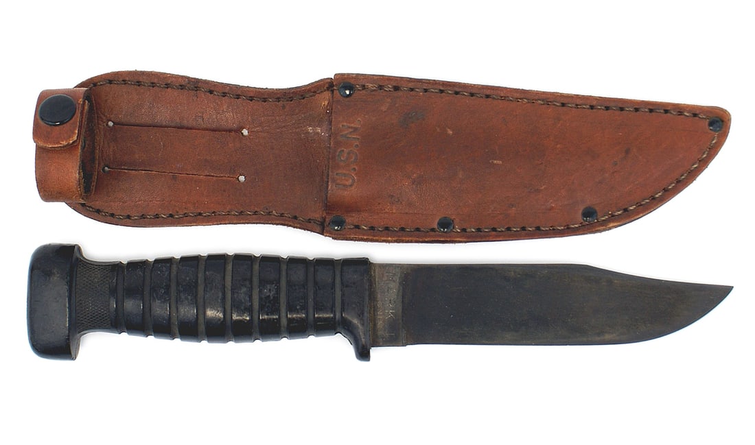 US WWII Colonial Navy MK 1 deck knife: D-040 U.S. WWII "Colonial" Navy MK-1 deck knife. Unsharpened, 5 1/8" parkerized blade marked "U.S.N. - MARK 1", in unused condition. Black molded rubber handle. Leather scabbard, marked "U.S.N., accom