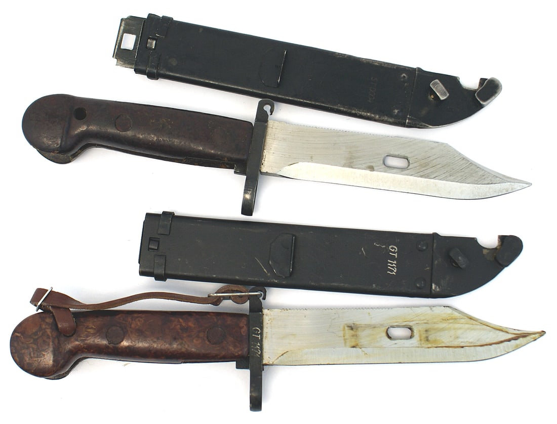 2 Soviet first pattern AK 47 bayonets: D-061 Lot of 2 Soviet first pattern AK-47 bayonets. Rounded pommel type plastic grips. Short crossguard/muzzle-ring. 5 7/8" stainless bowie-type blade with a serrated spine and elliptical hole near th