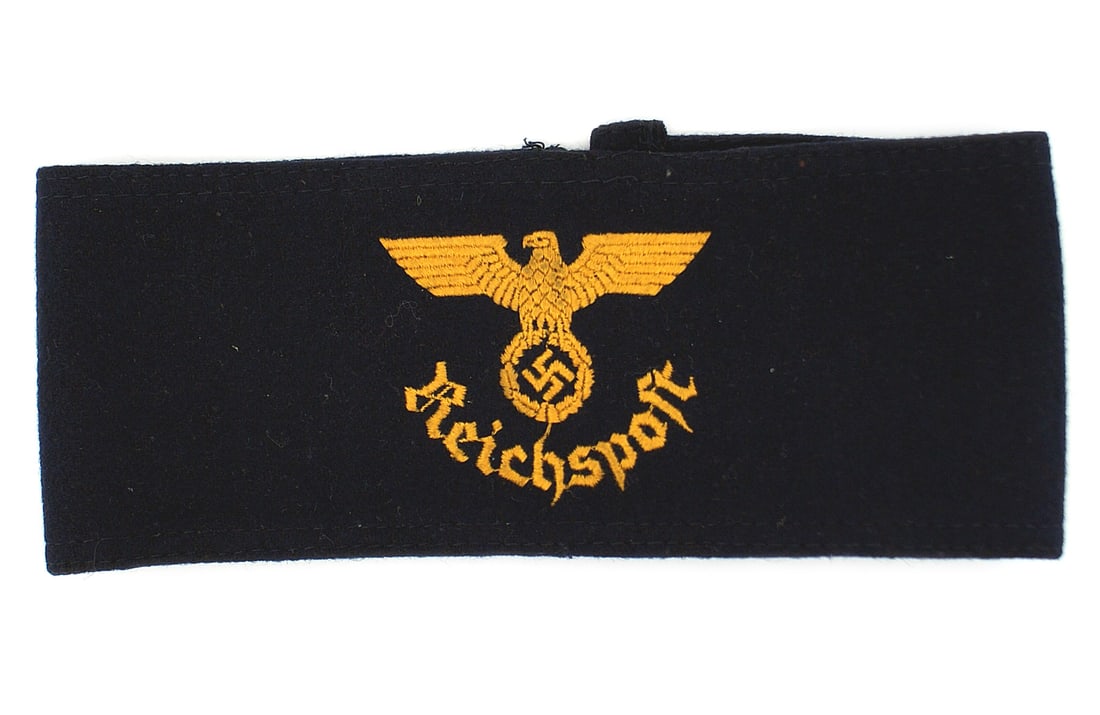 German WWII Postal Service armband: H-020 Third-Reich Postal Service armband. Machine embroidered yellow-gold eagle/swastika over "Reichspost" on a dark blue felt band. II