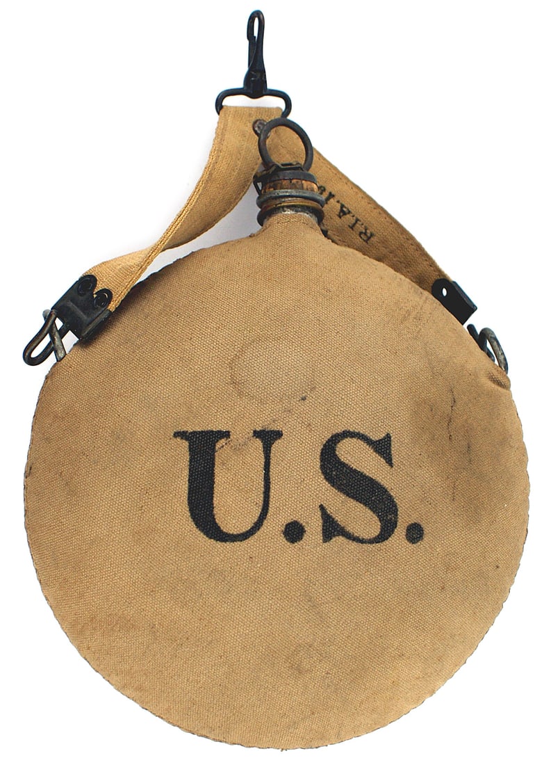 US Spanish American War 11th Cavalry canteen: K-041 U.S. Spanish-American War 11th Cavalry canteen. Canvas cover marked: "U.S." on one side and "NQ 65/E" , crossed swords and "11" on the other. Canvas hanger marked "RIA 1904". Also comes with bri