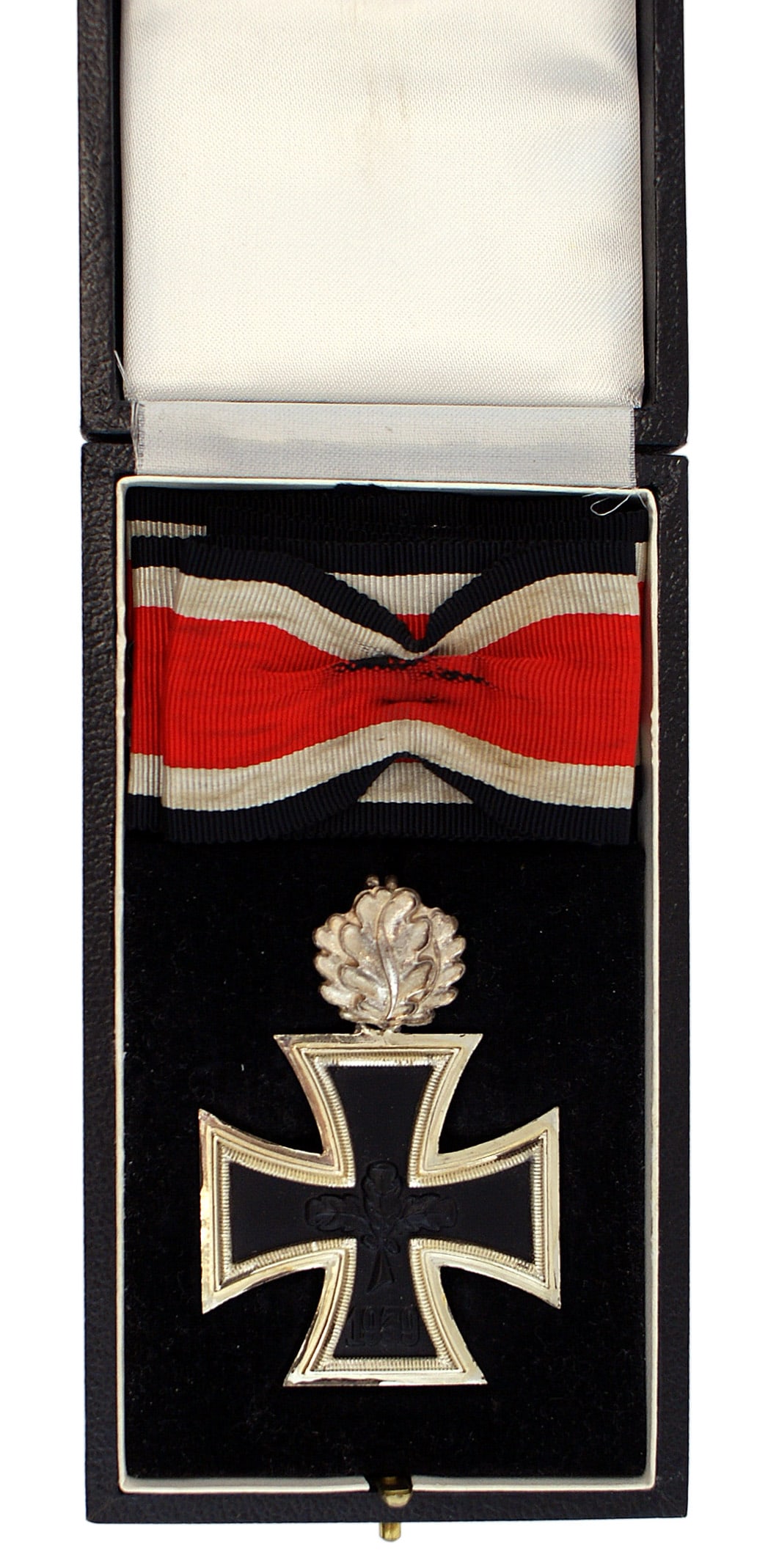 German 1957 lot Knights Cross Oak Leaves: B-085 German 1957 cased Knights Cross of the Iron Cross with Oak Leaves. The cross has three oak leaves and "1939" on the obverse of the black iron center. Reverse marked "1813". Silvered frame is mar