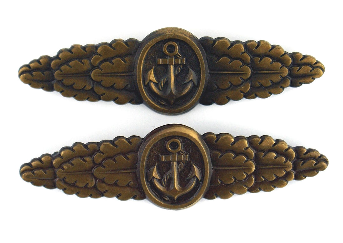 Lot of 2 German 1957 Naval Combat Clasps: B-091 Lot of 2 German 1957 Naval Combat Clasps. Round center panel holding a relief fouled anchor on a bar having arms decorated with oak leaves. Flat horizontal pin on reverse. Excellent. (Tom Breyet