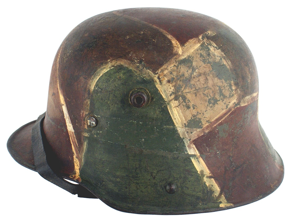 German WWI M1916 camouflage helmet: E-011 German WWI M1916 camouflage helmet. Unusual with a white border around the painted brown/green and tan assorted shaped panel. Three part leather liner, with original pads, shows field use. Black