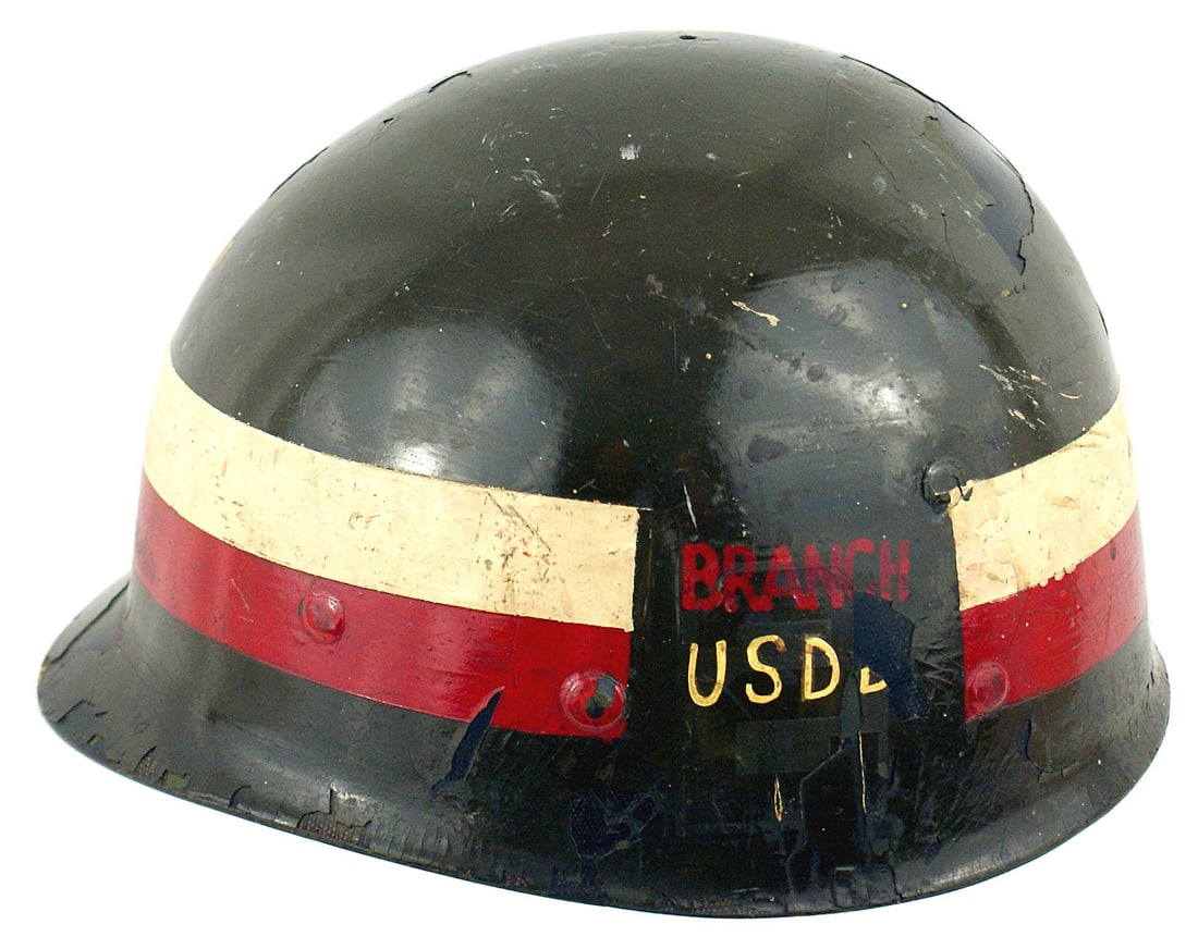 US helmet liner: E-063 U.S. helmet liner. O.D. repaint with a painted 2" white/red band. Also a 2nd Army insignia and "BRANCH USD..." appear on the sides. Shows wear and approximately 50% of the web straps remain. II-