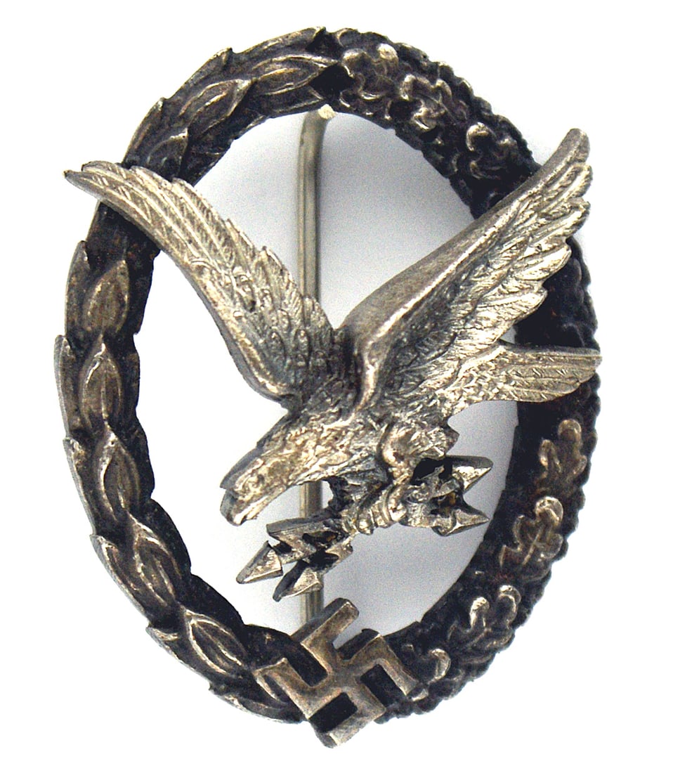 Luftwaffe WWII Radio Operator Air Gunner Badge: B-069 German Luftwaffe WWII Radio Operator/Air Gunner Badge. Heavy silver construction - a diving eagle holding "blitzen", is mounted on an open wreath of laurel/oak leaves with a swastika at the bott
