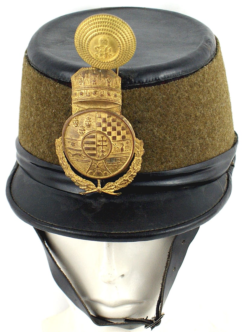 Hungarian WWI Hussar Officer shako: E-005 Hungarian WWI Hussar Officer's shako. Wide feld-grau band covers the dark red felt body of the helmet. Black leather top, visor, trim and chinstrap with a silver buckle. 4 1/4" x 2 1/2" gilt bra