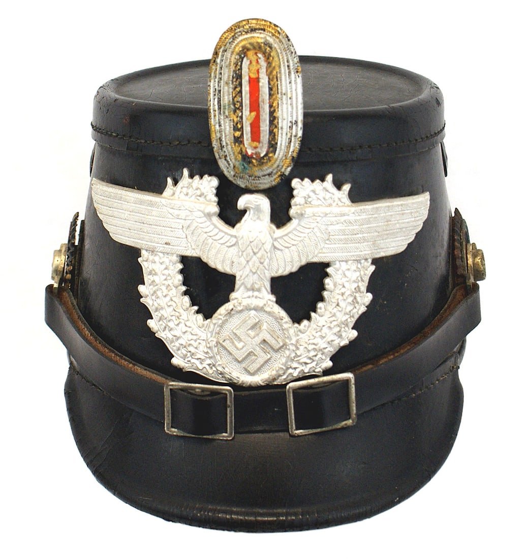German WWII black leather Police shako: E-019 Third-Reich black leather Police shako. Solid body. Flat top and Vulcan front visor. 2 3/4" x 6" relief white metal eagle/swastika 3/4" oak leaf wreath. Two-buckle, black leather chinstrap with