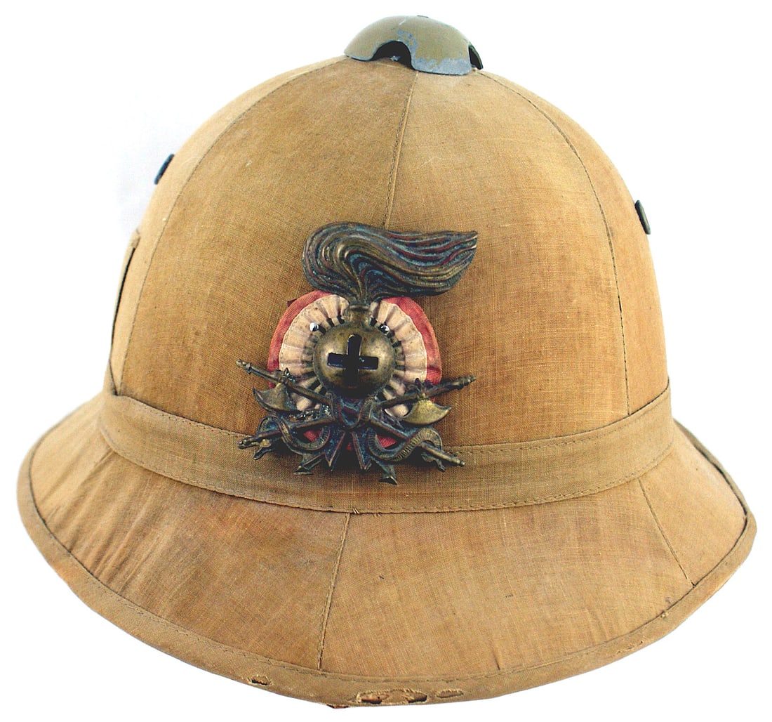 Italian WWII pith helmet: E-040 Italian WWII pith helmet. Tan cloth covered body with two screen air vents. Possibly a Medical unit associated with a large age toned brass flaming grenade with a black Geneva Cross on a pair of
