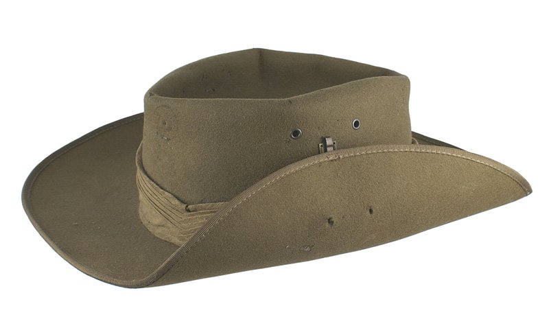 Australian WWII traditional military hat: E-201 Australian WWII traditional military hat. OD felt with a turned up side brim and cloth band. Leather sweatband and chinstrap. Minor wear and evidence of a front roundel and side badge. II