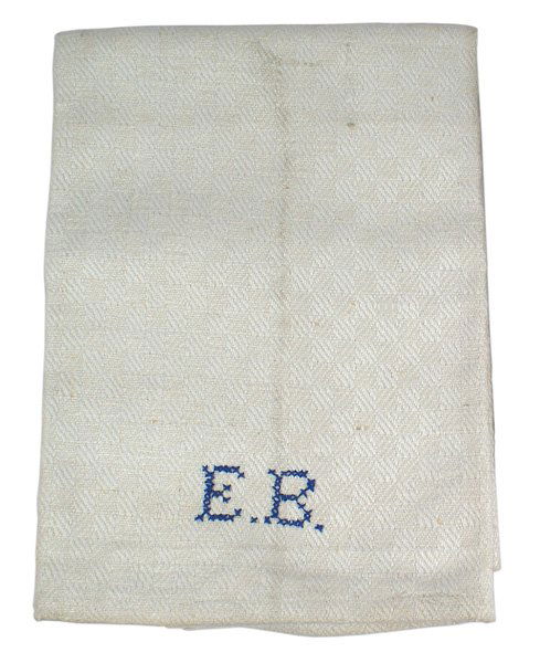 Eva Braun hand towel personal: A-40 Eva Braun hand towel. White cotton with a subdued pattern of continuous "diamonds". 7/8" high blue cross stitched initials "EB" near one border. Ribbon loops on the reverse on both ends. 37" x 17