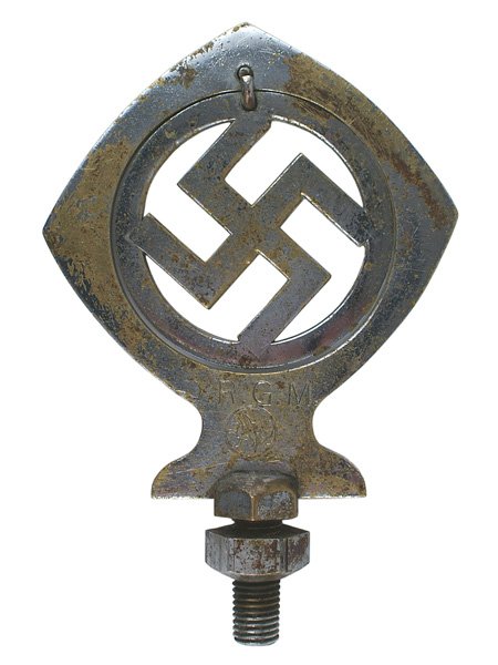 German WWII automobile ornament: H-201 Automobile fender/hood ornament. Nickeled brass 3 1/4" wide spear point with a cut-out center holding a free moving swastika within a disc. Marked with a griffen logo and "D.R.G.M." screw base p