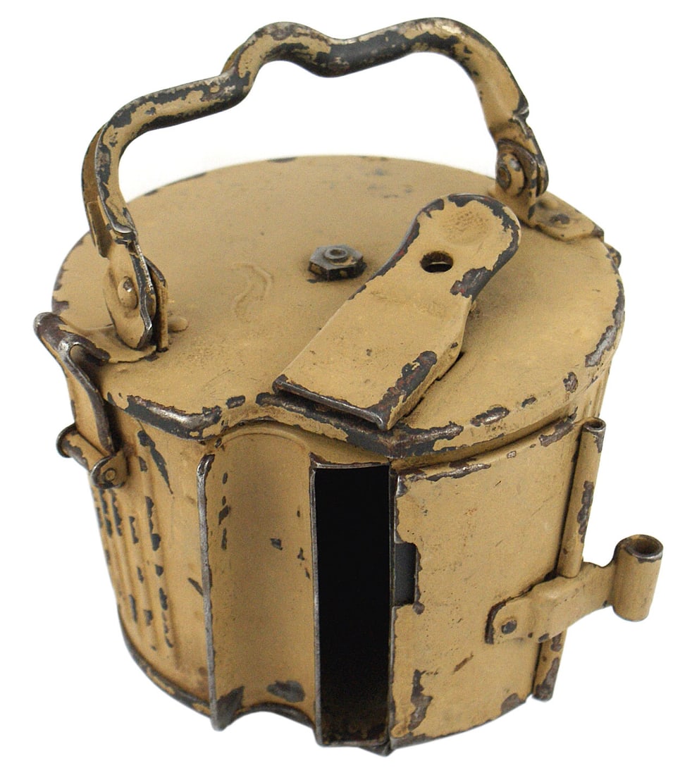 German WWII MG34 Afrika Korps drum magazine: M-053 German WWII MG-34 Afrika Korps 50-Round drum. AK painted tan "basket" with a sliding loading door folding handle and metal bracket for attaching to an MG-34. Some paint is worn but retains a