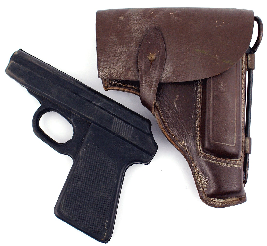 Rubber pistol and holster STEYR: M-072 Unknown hard rubber simulated automatic pistol. Holster shaped might suggest a 1907 Dreyse, 1908 STEYR or a 1912 FROMMER. The dark brown leather holster has an extra magazine holder on the outsi