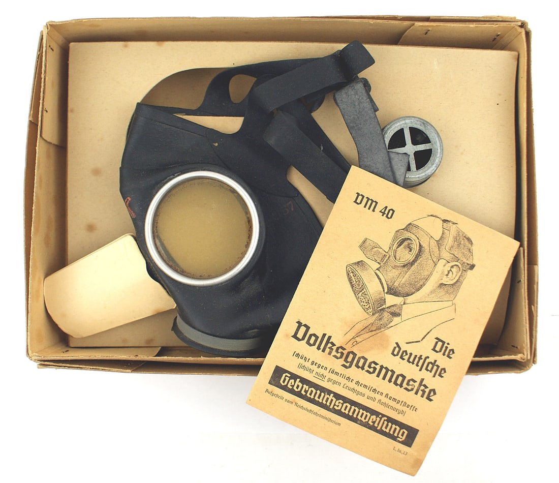 German WWII Volksgasmaske gas mask: N-005 German WWII "Volksgasmaske". Rubber face mask with lenses and "pancake" air filter. In original box with an illustrated pamphlet of how to assemble and use. With original cardboard box. II