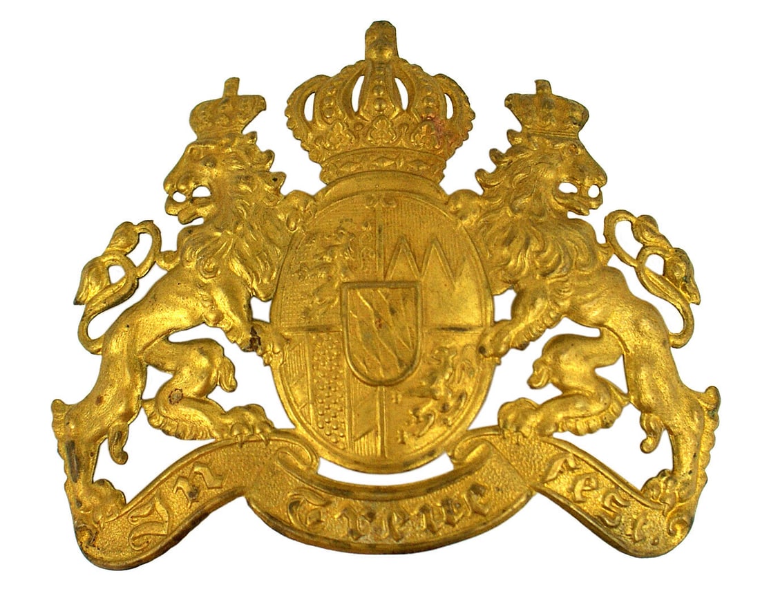 Imperial Bavarian brass helmet plate: E-017 Imperial Bavarian other ranks brass helmet plate. Brass crowned State coat-of-arms between two lions - on a legend with "IN TREUE FEST". 3 1/2" x 4 3/4". Two wire loops on reverse. Circa 1900. I