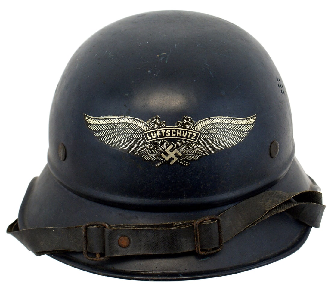 German WWII Air Defense gladiator helmet: E-026 German Third-Reich Luftschutz (Air Defense) one-piece "gladiator" type helmet. Dark-blue finish with minor wear. Large winged swastika "Luftschutz" decal on front. Five double tongue ersatz line