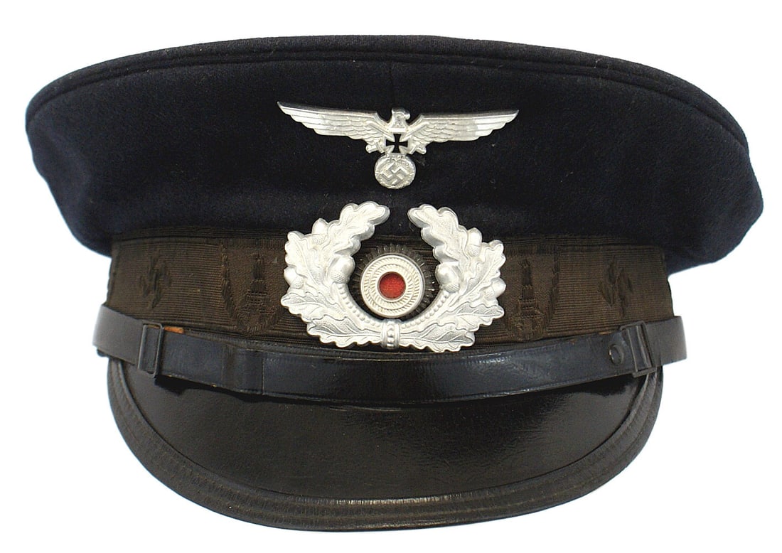 German WWII War Veterans Support peaked cap: E-033 German Third-Reich "Kyffhauserbund" (War Veterans Support Association) peaked cap. Dark blue wool body with a black ribbon band (embossed with alternating swastikas and shield/monument). Black l