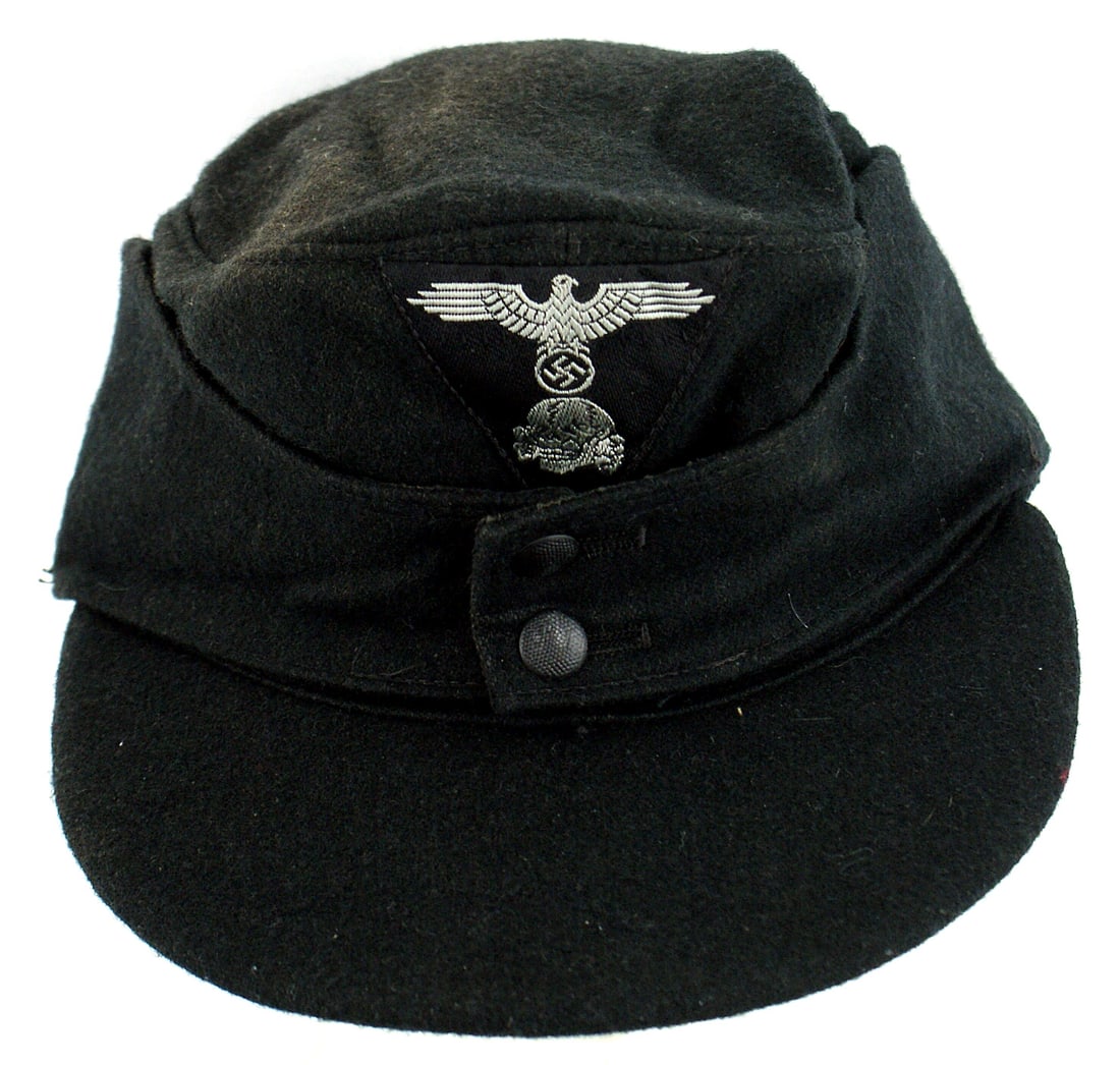 German WWII Waffen SS 1st type M43 cap: E-034 German WWII Waffen-SS 1st type M-43 cap. Black wool body and covered brim. Machine-sewn, bevo embroidered eagle/swastika/skull, silver on black trapezoid. Two-button front can be unbuttoned and 
