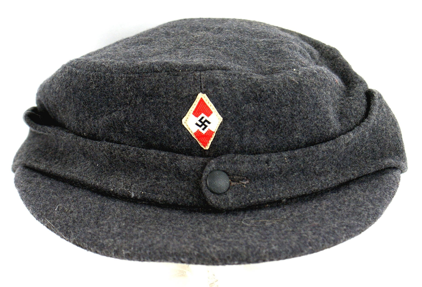 German WWII Hitler Youth field cap: E-035 German WWII Hitler Youth field cap. Similar to an M-43 but blue-gray wool with a sewn-on bevo red/white/swastika/H.J. diamond. One button on front, when unbuttoned a pull-down folded cloth cover