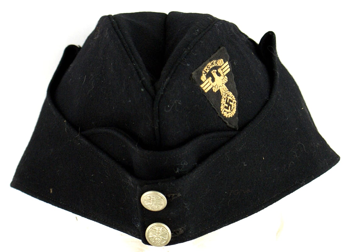 German WWII NSKK overseas cap: E-036 German Third-Reich NSKK black fine wool o'seas cap. Two NSKK buttons on front. Left side has an inverted bevo triangle with "NSKK" legend/eagle/swastika. Folded side material un-buttons and fold