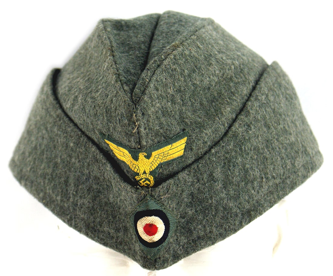 German WWII Navy Coastal Artillery overseas cap: E-040 German WWII Navy Coastal Artillery E.M. o'seas cap. O.D. wool with gold bevo eagle/swastika and rosette sewn to front. Satin-like gray lining has a "PARIS" ink stamping. I