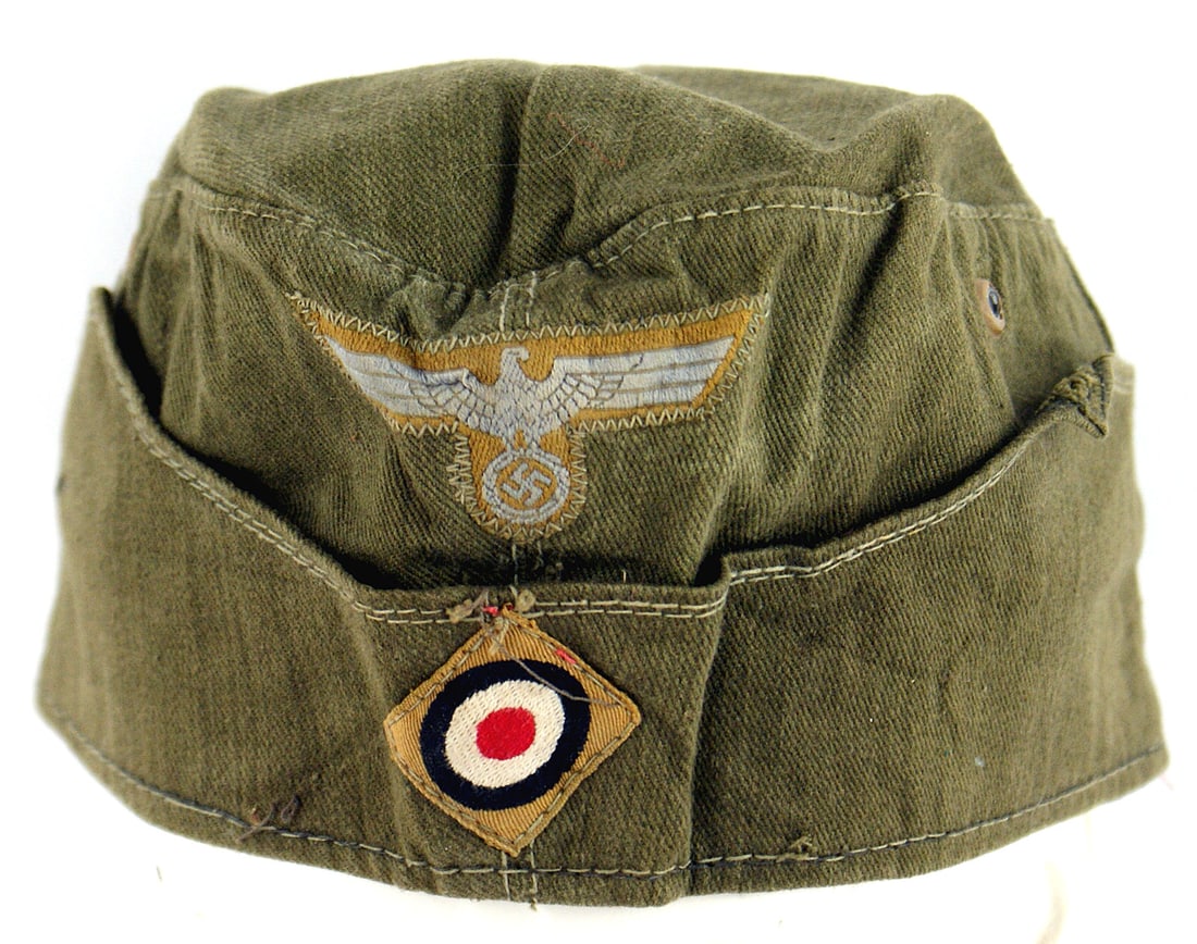German WWII Afrika Korps EM overseas cap: E-041 German WWII Afrika Korps E.M. o'seas cap. O. D. fabric with a machine sewn bevo AK eagle and rosette. Red cloth lining marked with size "53" and faint name of maker "Wek... Glaud...". II