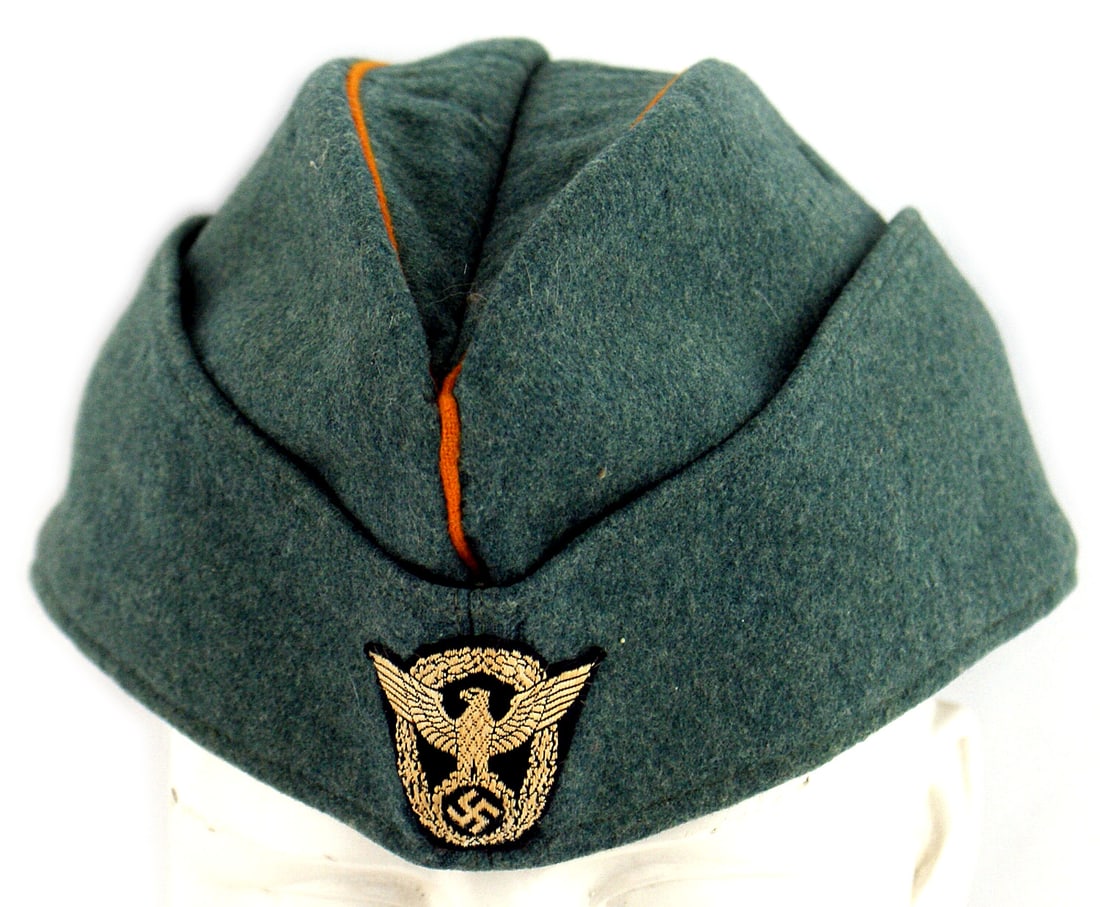 German WWII Feldgendarmerie overseas cap: E-044 German Third-Reich "Feldgendarmerie" fine wool o'seas cap. Bevo embroidered Police eagle/swastika/wreath. Orange piping. Faint maker's ink stamping on gray cloth lining. Excellent. I