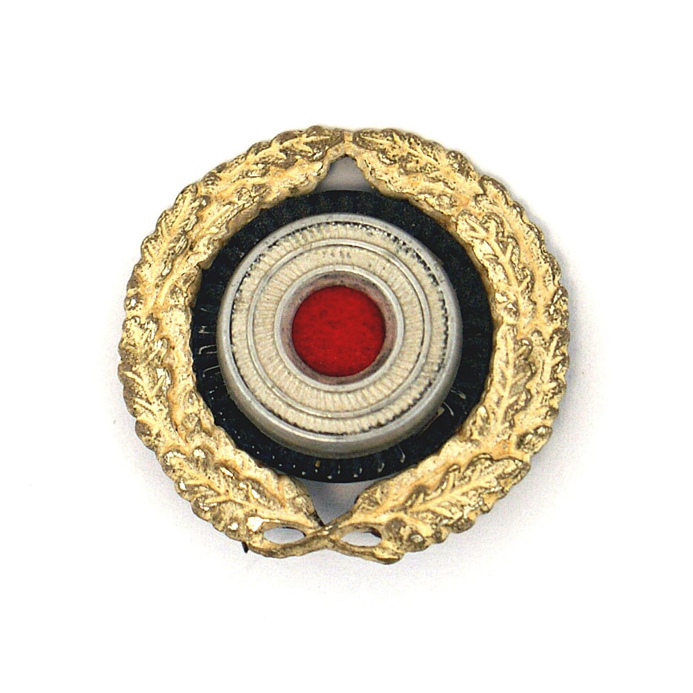 German WWII peaked cap insignia Postal RLB: E-054 Lot of 2 Third-Reich peaked cap insignia: (1) Postal Official. Narrow silvered oak leaf wreath around a rosette. (2) RLB. 5 1/8" straight wings with an affixed rosette within a center linden lea