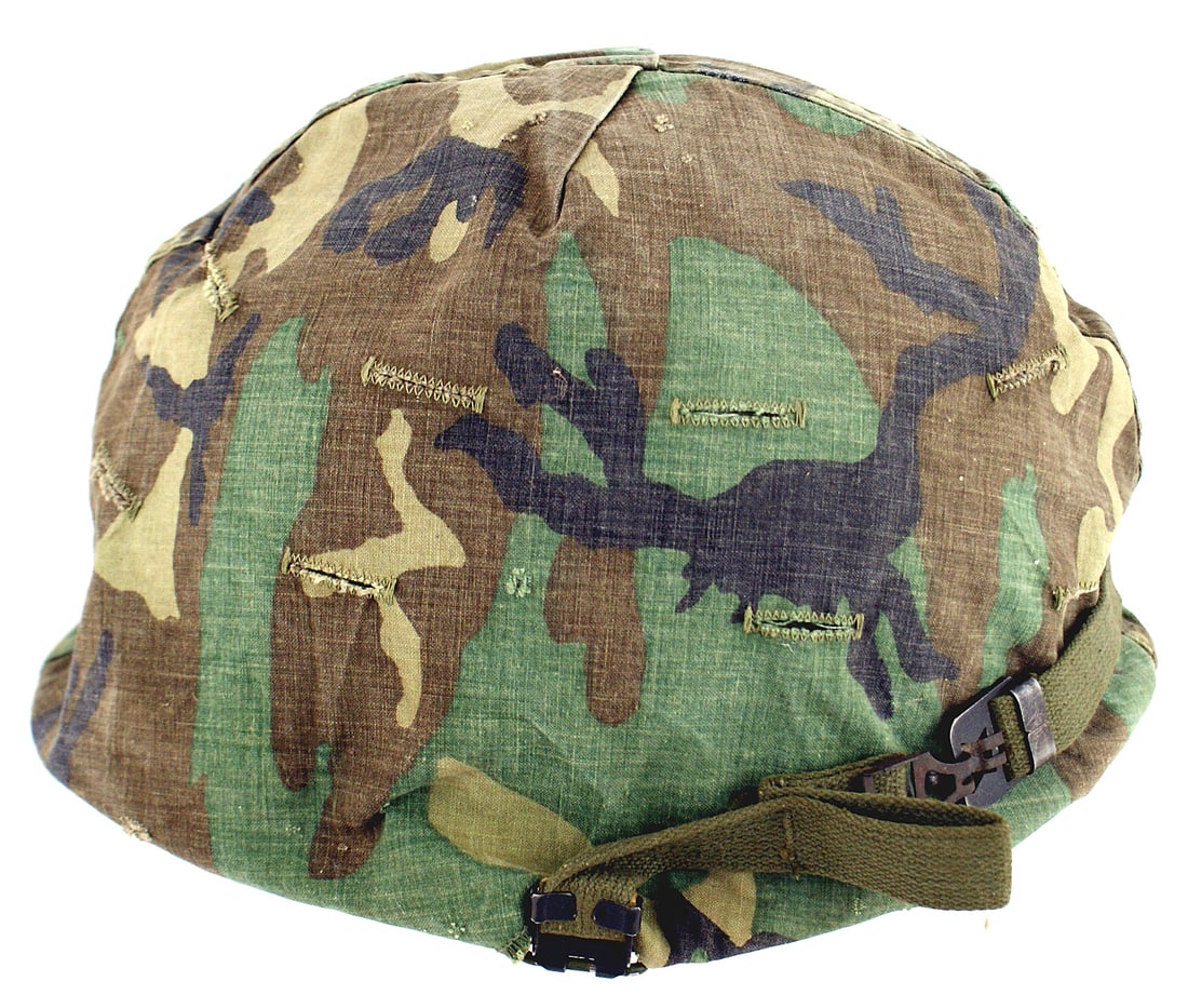 US post WWII sand finish helmet: E-059 US post-WWII "sand" finish folding bale helmet. With a camouflage green/brown/tan/black "splotch" pattern cover. O.D. fiber liner with the residue of several decals, including the 27th Armored D