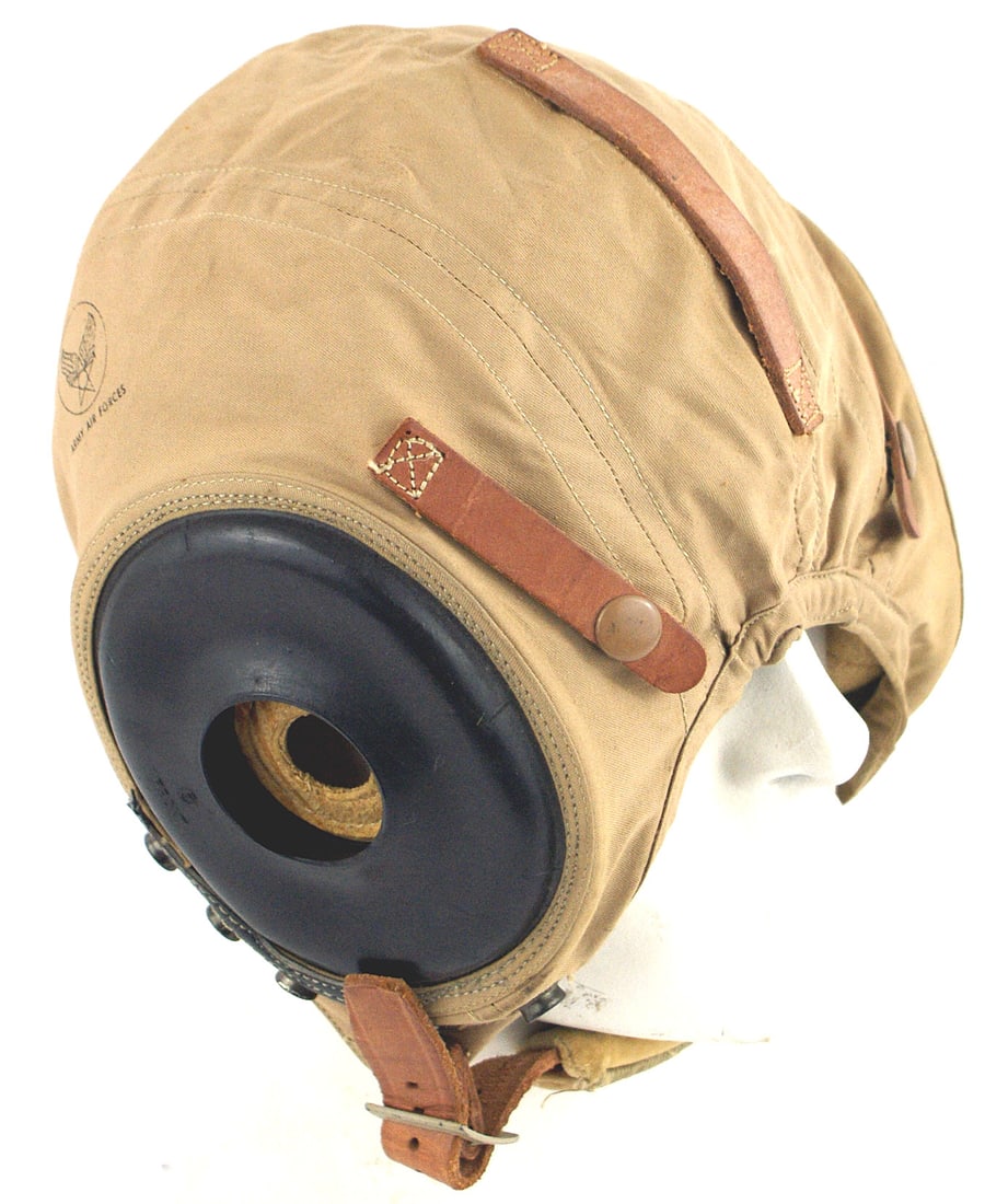 US WWII Army Air Force pilot helmet: E-062 US WWII Army Air Force Type A-11 tan canvas summer pilot's helmet. Sewn-in rubber earphone holders. Rubber strip with 4 buttons for snap buttons. Three leather strips on helmet. Padded chinstrap