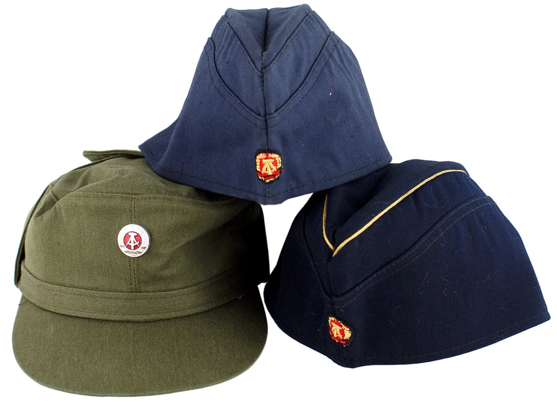Lot of 5 DDR East Germany military caps: E-081 Lot of 5 DDR (East Germany) military caps: (1) Ski cap/M-43 style cap. Smooth O.D. coat-of-arms. Brown leather sweatband and a cloth lining. Marked "NVA IV/Y" and with size "57". Stiff brim cove