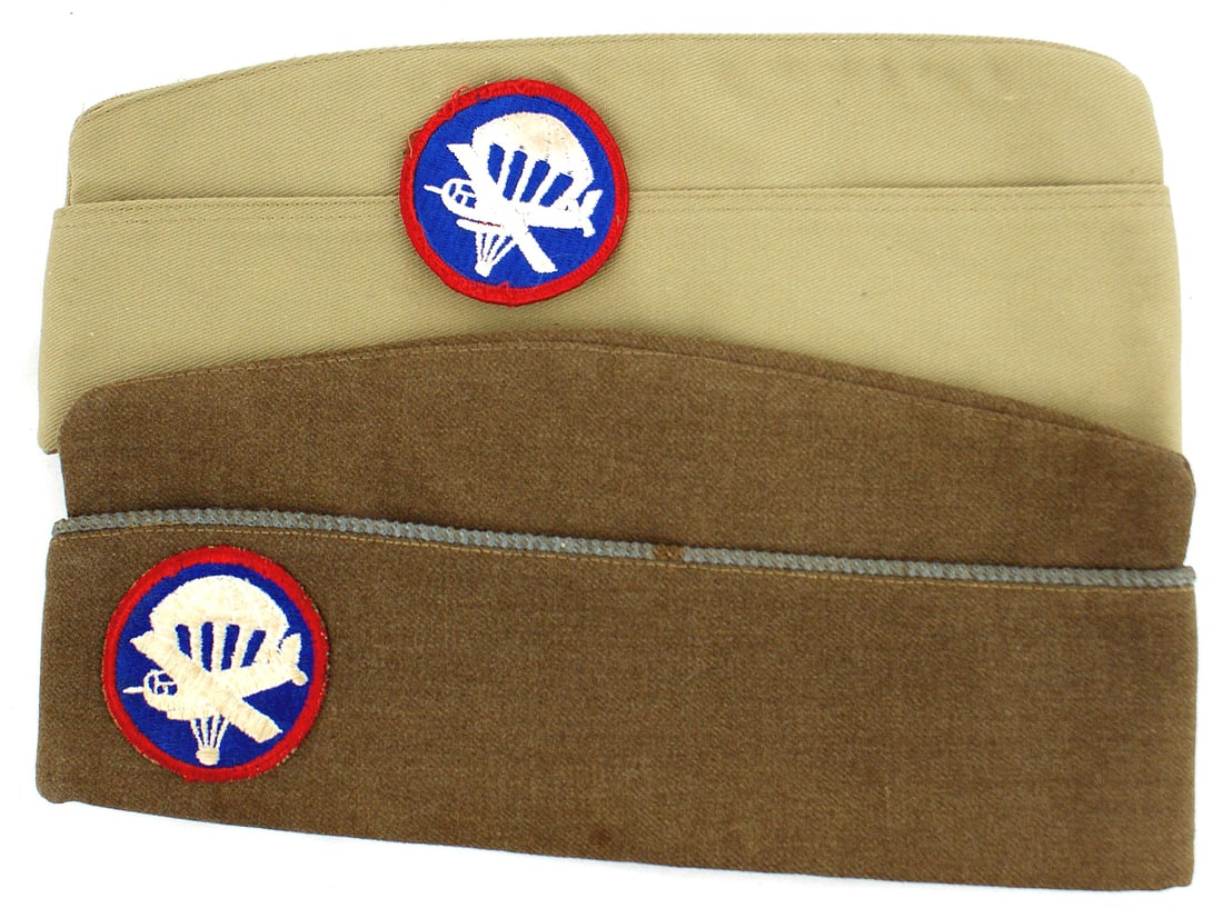 Lot of 2 US WWII Para Glider overseas caps: E-098 Lot of 2 US. WWII Para/Glider o'seas caps: (1) Officer's O.D. wool cap with blue piping and sewn-on embroidered parachute/glider "patch". Soft leather sweatband and silk lining. (2) E.M. tan cot